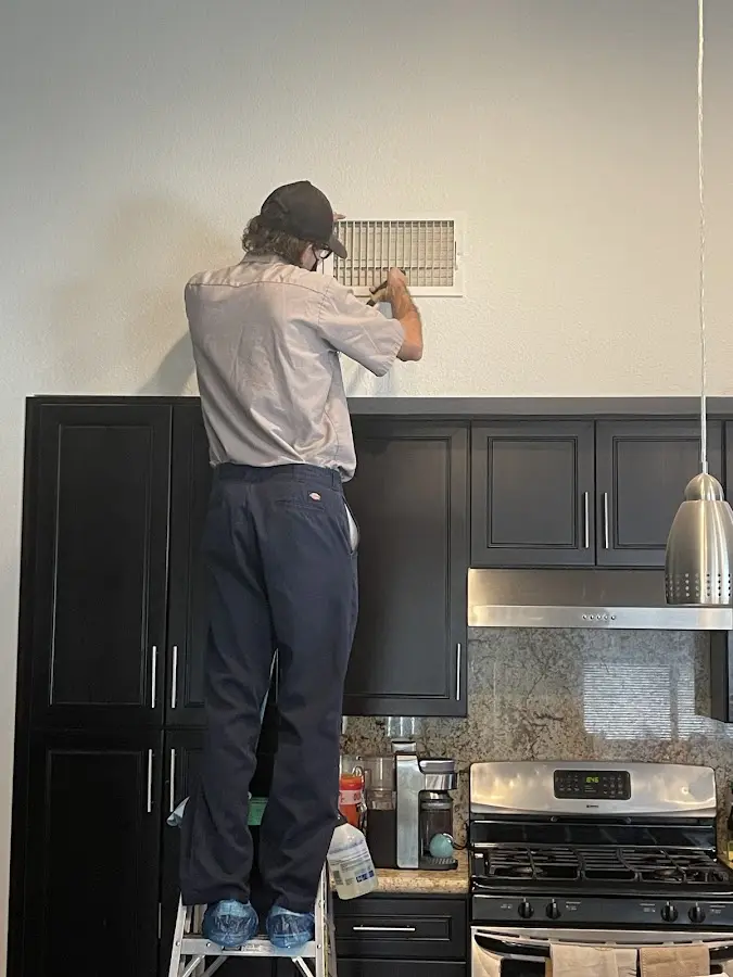 Technician inspecting an air vent during HVAC service in Vinings